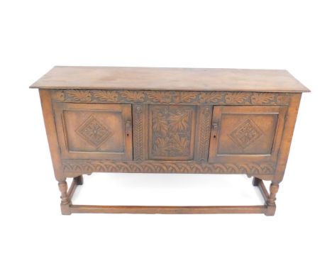A Victorian 17thC style oak sideboard, the oak leaf carved frieze over two panelled doors enclosing a central panel, carved w