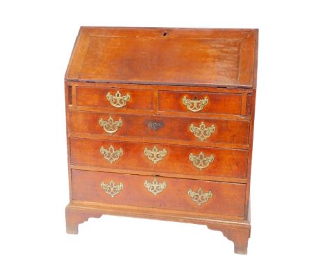 A George III oak bureau, the fall opening to reveal a central drawer flanked by recesses and six drawers, over two short and 