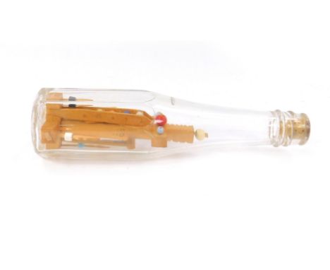 A Cambridgeshire folk art carving in a bottle, carved with a cross shaped stand holding various tools, marked in pencil made 