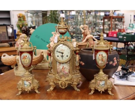 A late 19th Century gilt metal clock garniture with porcelain mounts, the clock with urn finial, enamel dial above a porcelai