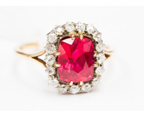 A yellow gold synthetic ruby and diamond ladies cluster ring, the multi-faceted ruby surrounded by small, brilliant cut diamo