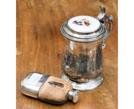 A white metal lidded tankard with enamelled ceramic lid cartouche, together with a plated hip flask