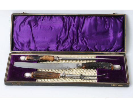 An Edwardian cased English silver and horn handled three piece carving set comprising a knife, a skewer and two pronged fork 