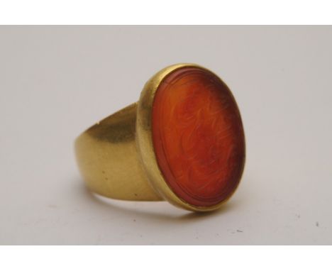 A high carat gold ring set with an oval carnelian intaglio seal carved with Islamic or Arabic script