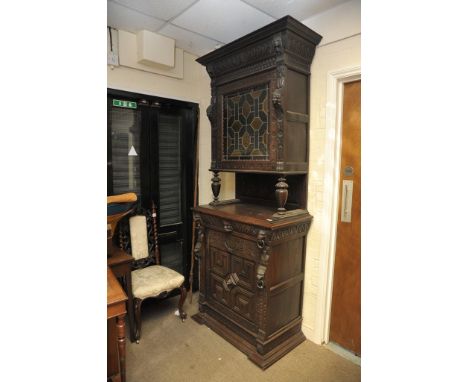 A late 19th century Flemish carved oak bookcase with coloured lead light glazed door