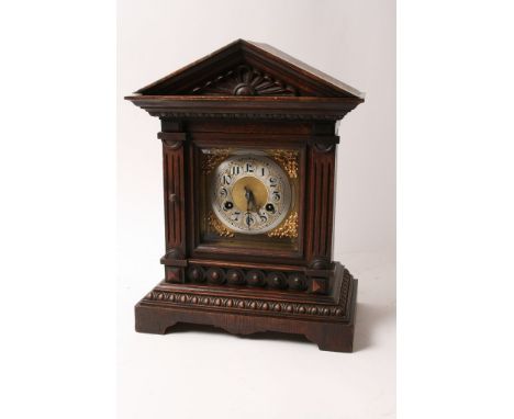 An oak cased mantle clock having square brass dial and silvered chapter ring with Arabic numerals