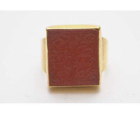 A high carat yellow gold ring inset with a carnelian intalgio seal carved with Islamic or Arabic script