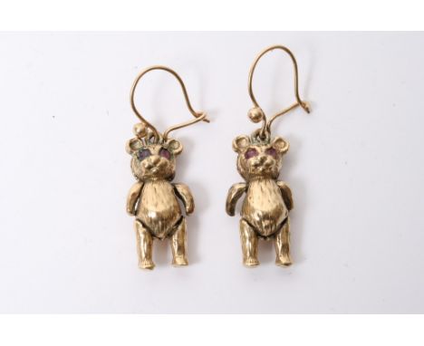 A pair of gold earrings in the form of teddy bears.