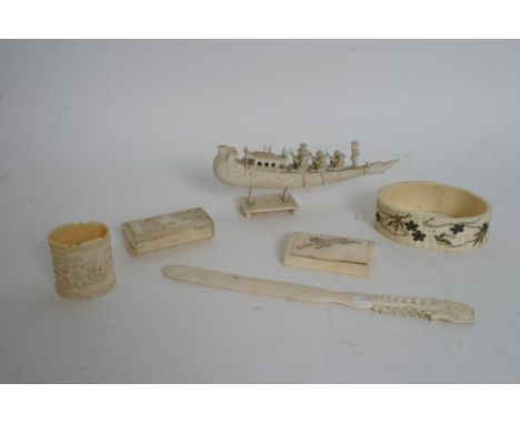 A collection of six items of ivory including two snuff boxes, a page turner, napkin ring and a model of the ceremonial boat. 