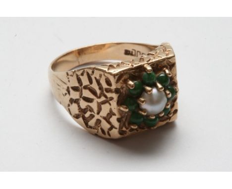 A gold ring with central flower design of green stones and single pearl