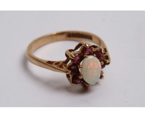 A 9ct gold ring inset with an opal cabochon flanked by Ruby's