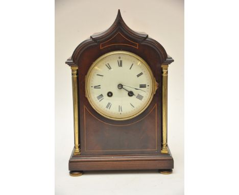 An Edwardian inlaid mahogany mantel clock the dial flanked by brass pillars.
Glass bezel cracked