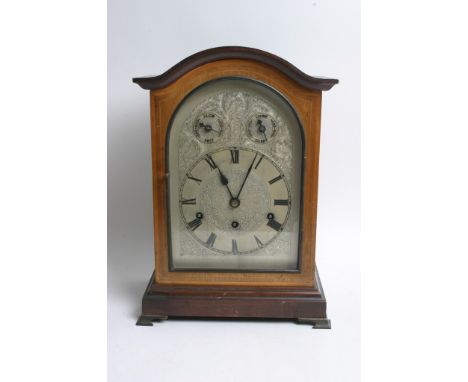 A mahogany cased mantle clock having arched silvered dial and Roman numerals