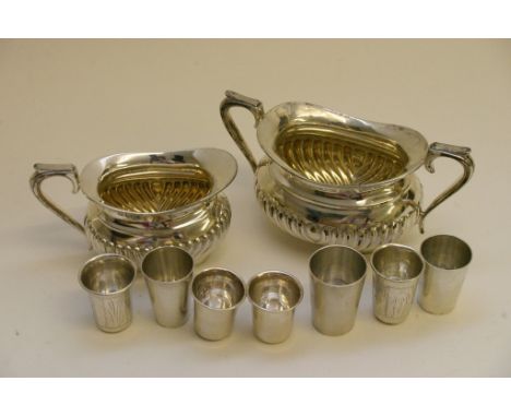 A lobed silver cream jug and matching sucrier plus a collection of continental silver shot glasses