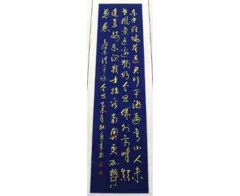 A Chinese silk mounted calligraphy scroll in gold ink on a blue painted background, W. 42cm.