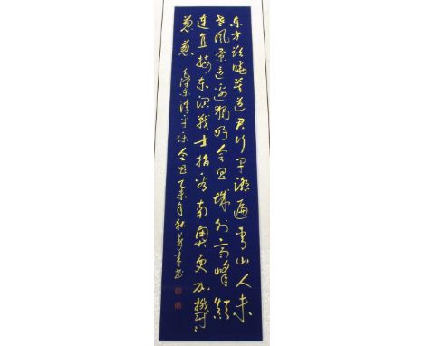 A Chinese silk mounted calligraphy scroll in gold ink on a blue painted background, W. 42cm.