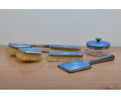 A 1920's silver and blue enamel dressing table set, comprising two large and two small brushes, a mirror and cut glass based 