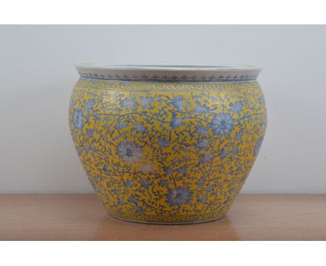 A large Chinese ceramic fish bowl, the exterior with a yellow ground and foliate scrolling blue decoration, the inside decora
