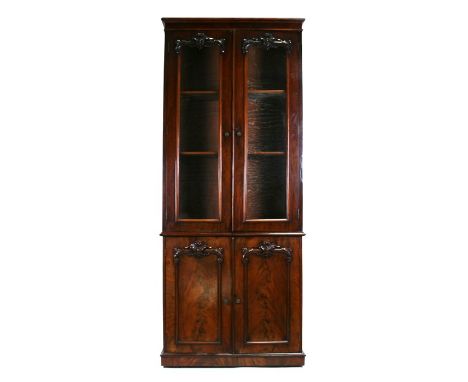 A Victorian mahogany bookcase on cupboard, the upper section with twin glazed doors enclosing shelves, the bottom section wit