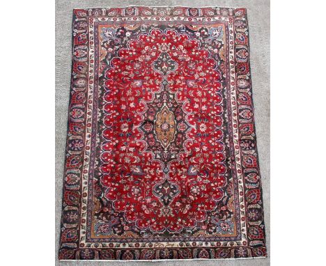 A Persian Mashad woollen hand knotted carpet with central floral medallion within floral borders on a red ground, 266 by 160c