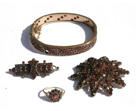 A Victorian suite of yellow metal garnet mounted jewellery to include a bangle, brooches and a ring (4).