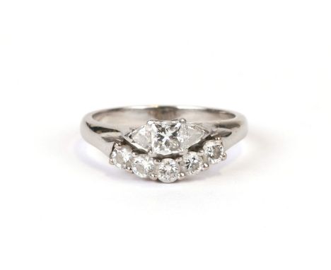 A platinum and diamond ring (tested) set with a Princess cut diamond flanked by two trillion cut diamonds and five round bril