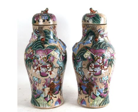 A pair of large Chinese crackle glaze vases and covers decorated with warriors in enamel colours, with applied dragons to the