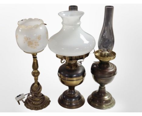 Two brass oil lamps and a table lamp.