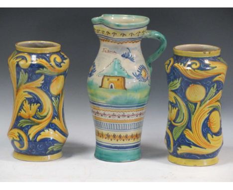 A pair of Albarello tin glaze jars, 25cm tall, and a jug decorated with filred and a bird, 30.5cm tall (3)