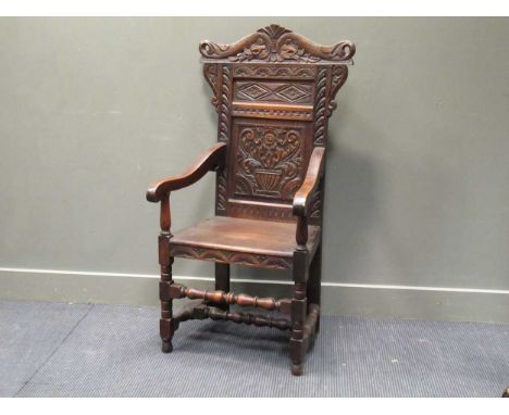 A Victorian oak wainscot elbow chair with carved back panel surmounted by scrolling serpents 125 x 66 x 53cm