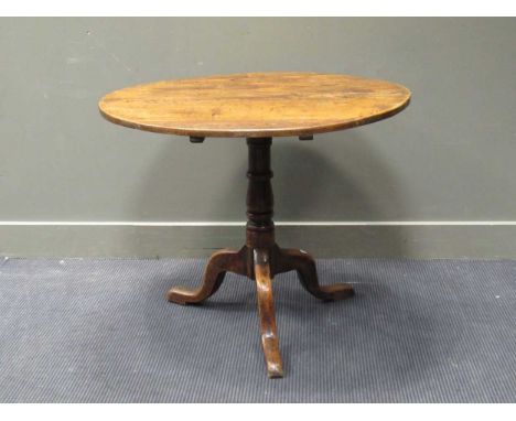 An elm topped circular tripod table, 19th century, the circular tilt-top over a turned column support raised on cabriole legs