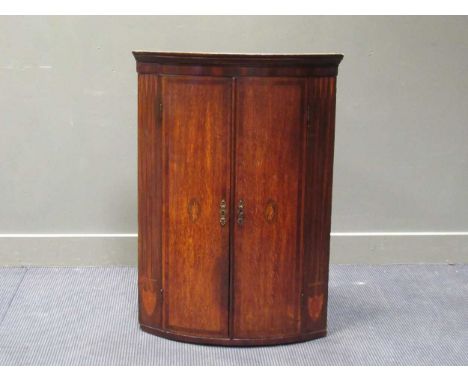 A George III inlaid oak two door bow front corner cupboard with painted interior, 101 x 72 x 48cm