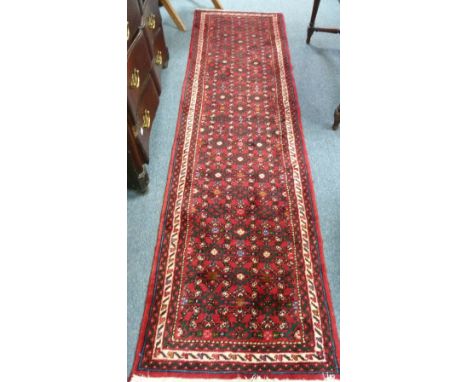 Tribal rugs; a red ground Hamadan runner, woven with with stylized floral design, set within a geometric border.