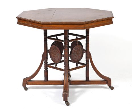 A Liberty's style walnut lamp table, on a turned base with carved roundels decorated flowers, 74 cm high x 90 cm wide 