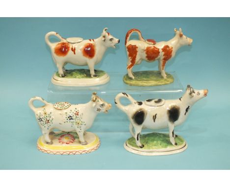 A Staffordshire-style ceramic cow creamer, the body with floral decoration, 12.5cm high and three other ceramic cow creamers,