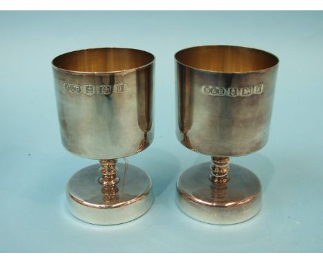 A pair of modern silver goblets of squat form, each with slightly-tapered bowl and knopped stem raised on circular base, make