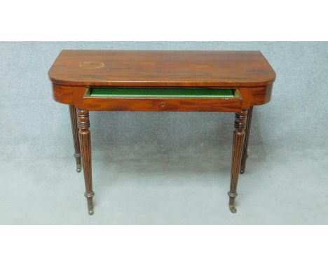 A late Georgian figured mahogany console table fitted with frieze drawer on turned tapering supports terminating in brass cup