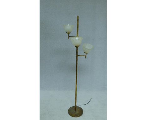 A vintage floor standing brass lamp standard with three branches fitted with opaque glass uplighter shades. H.155cm 