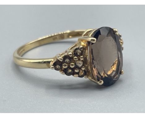 Ladies 9ct gold smokey quartz ring featuring a oval shaped stone in centre and 6 small Smokey quartz on each shoulder 2.82g s