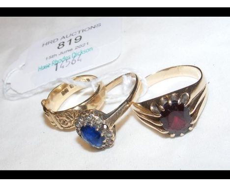 A garnet ring in gold setting together with two others