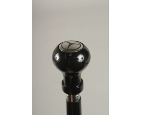 A WOODEN WALKING STICK WITH MERCEDES HANDLE.