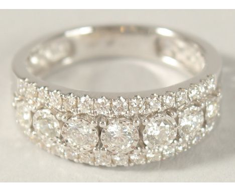 AN 18CT WHITE GOLD AND DIAMOND HALF HOOP RING.
