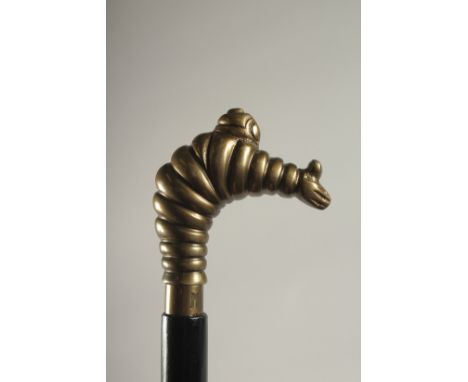 A WOODEN WALKING STICK WITH A MICHELIN MAN HANDLE.