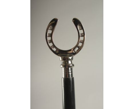 A WOODEN WALKING STICK WITH A HORSESHOE HANDLE.