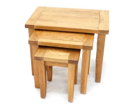 A nest of three light oak tables, of plain form, on tapering legs, 68cm wide. 