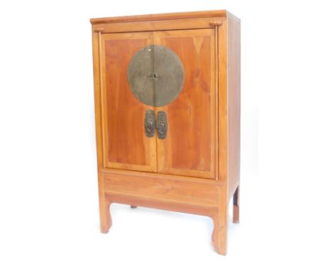 A Chinese pine cupboard, the two doors with silver plated mounts enclosing a shelf and drawers, on shaped legs, 182cm high, 1