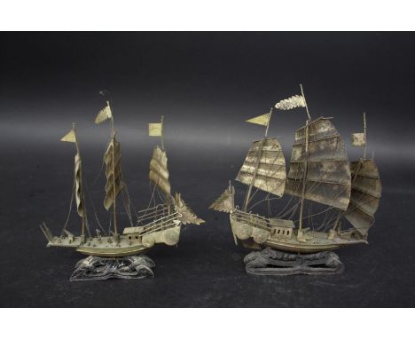 TWO CHINESE MODEL JUNKS probably silver, the masted boats mounted on wooden stands. With Chinese character marks to the end o