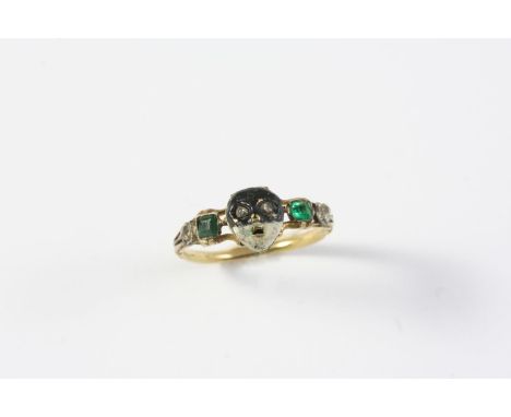 AN 18TH CENTURY ENAMEL, DIAMOND AND EMERALD MEMENTO MORI RING the hinged mask section with black and white enamel decoration 