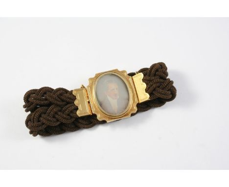 A VICTORIAN GOLD AND HAIR WORK MOURNING BRACELET centred with a gold mounted portrait of the head and shoulders of a gentlema