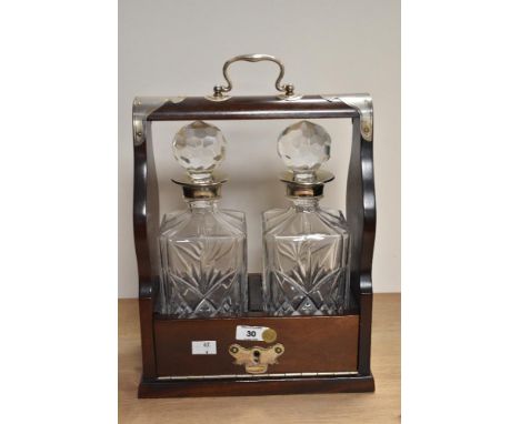A modern reproduction silver-plate mounted mahogany two bottle tantalus, with lockable fall-front and two canted square secti